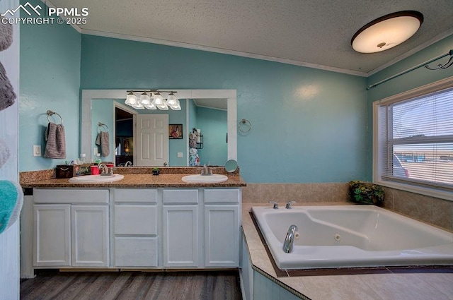 bathroom featuring a textured ceiling, vaulted ceiling, ornamental molding, a relaxing tiled tub, and vanity