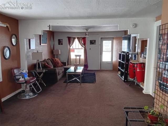 living room with ceiling fan, carpet flooring, and a textured ceiling