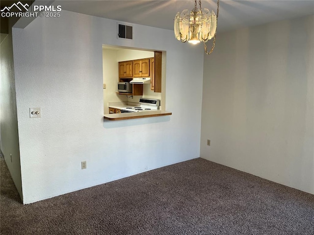 carpeted spare room featuring an inviting chandelier