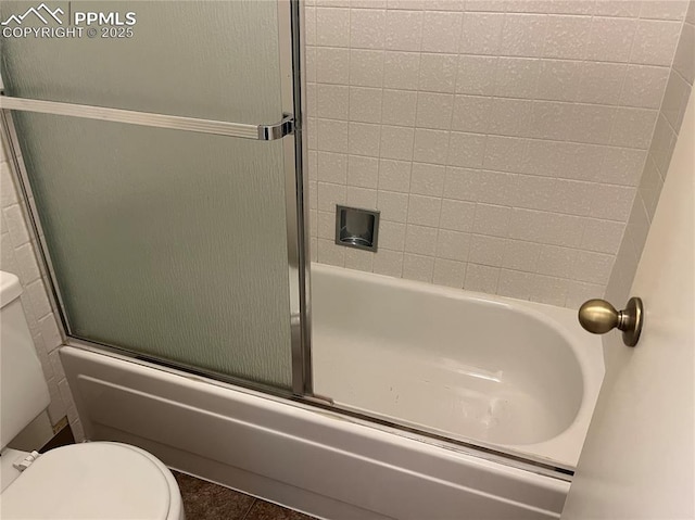 bathroom with toilet and bath / shower combo with glass door