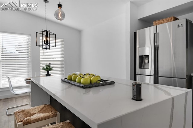 kitchen with decorative light fixtures, an inviting chandelier, a kitchen bar, hardwood / wood-style floors, and stainless steel fridge with ice dispenser