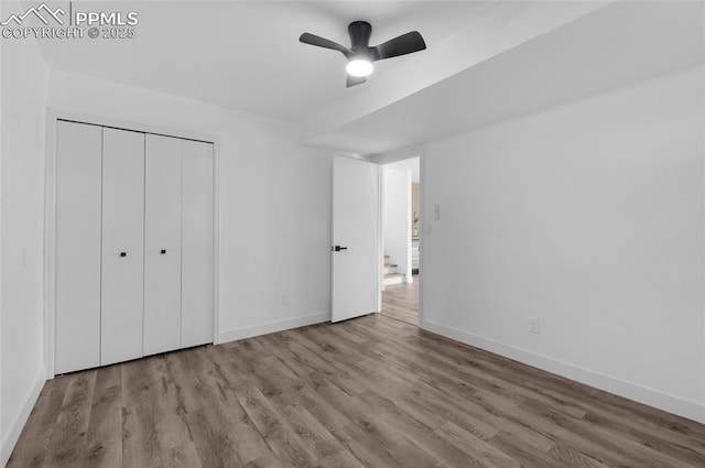 unfurnished bedroom with ceiling fan, light wood-type flooring, and a closet