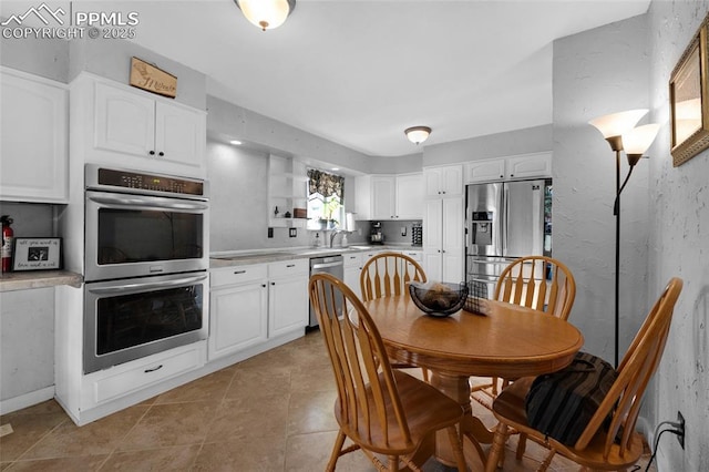 kitchen featuring sink, white cabinets, stainless steel appliances, and light tile patterned flooring