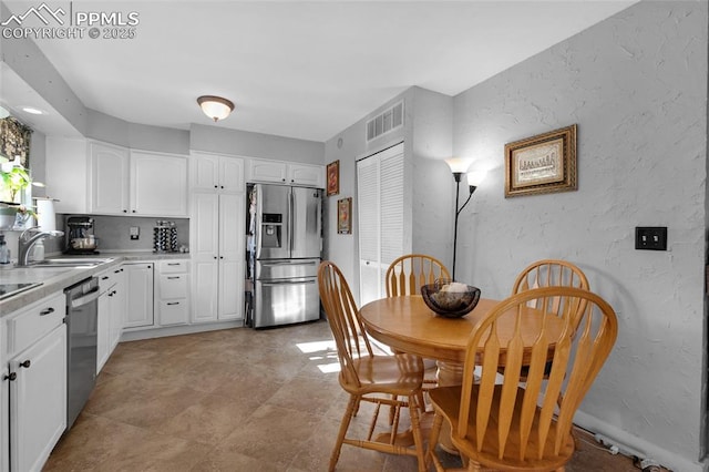 kitchen featuring appliances with stainless steel finishes, backsplash, white cabinetry, and sink