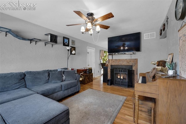 living room with ceiling fan, wood-type flooring, and a fireplace