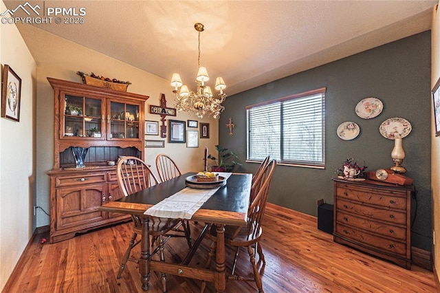 dining space with wood-type flooring and an inviting chandelier