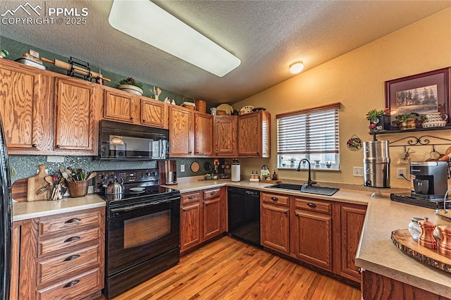 kitchen with sink, a textured ceiling, lofted ceiling, light hardwood / wood-style floors, and black appliances