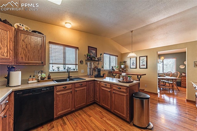 kitchen with kitchen peninsula, pendant lighting, plenty of natural light, black dishwasher, and sink