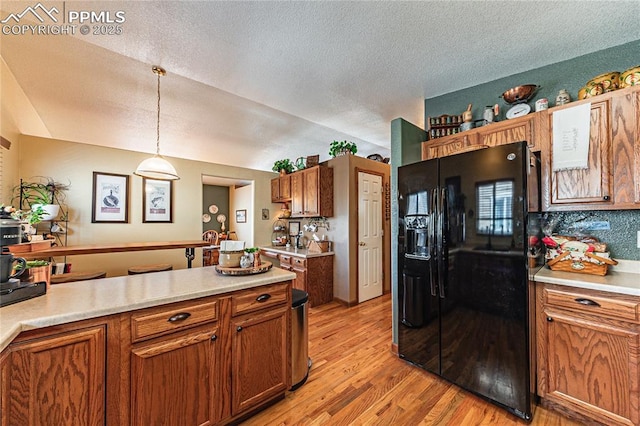 kitchen featuring black fridge with ice dispenser, a textured ceiling, vaulted ceiling, light hardwood / wood-style flooring, and hanging light fixtures