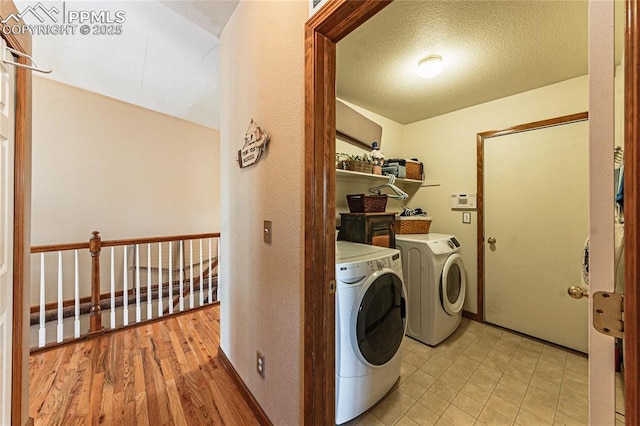 laundry room featuring light hardwood / wood-style floors, a textured ceiling, and independent washer and dryer