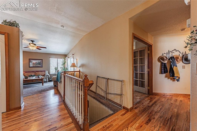 hallway featuring a textured ceiling, hardwood / wood-style floors, and vaulted ceiling