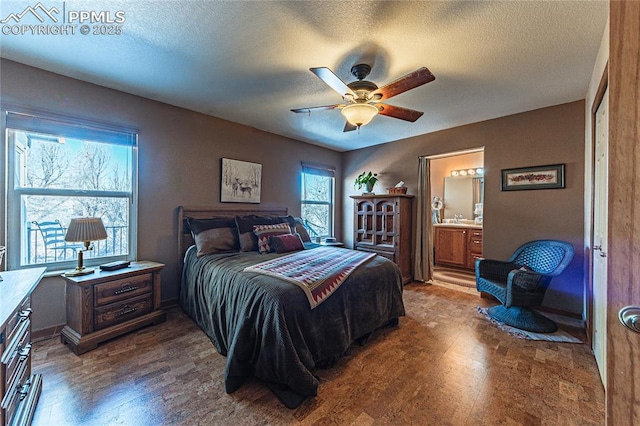 bedroom with ceiling fan, ensuite bath, a textured ceiling, and wood-type flooring