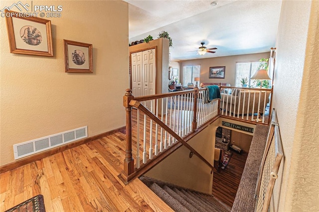 staircase with ceiling fan and hardwood / wood-style floors