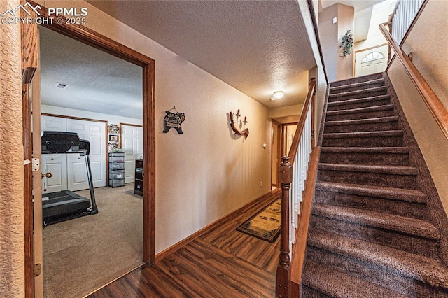 stairs with a textured ceiling and hardwood / wood-style floors