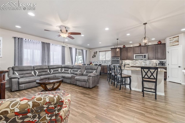 living room featuring ceiling fan, light hardwood / wood-style floors, and sink