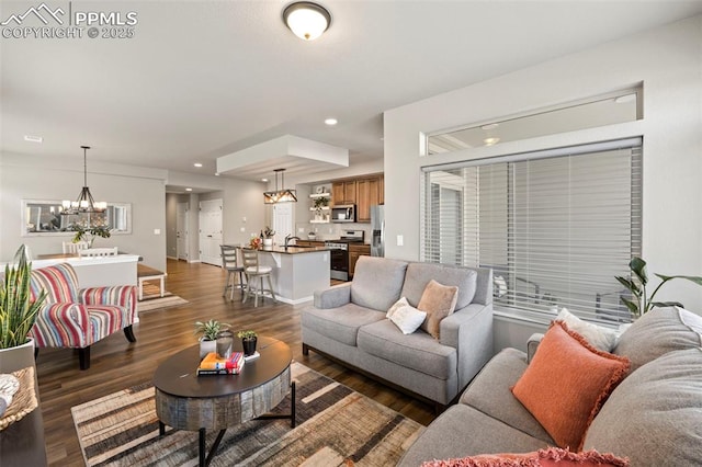 living room featuring dark wood-type flooring, sink, and an inviting chandelier