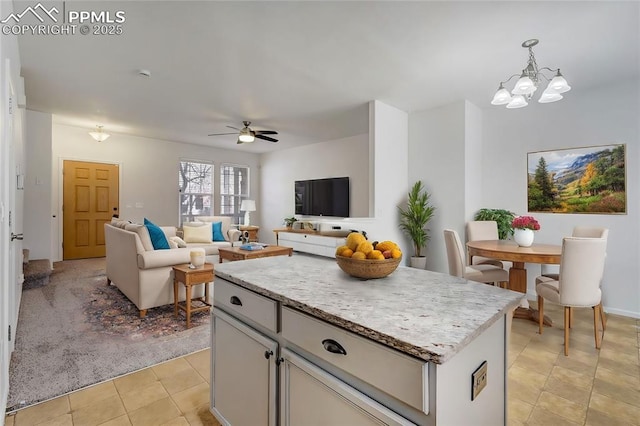 kitchen with hanging light fixtures, a center island, ceiling fan with notable chandelier, and light tile patterned floors