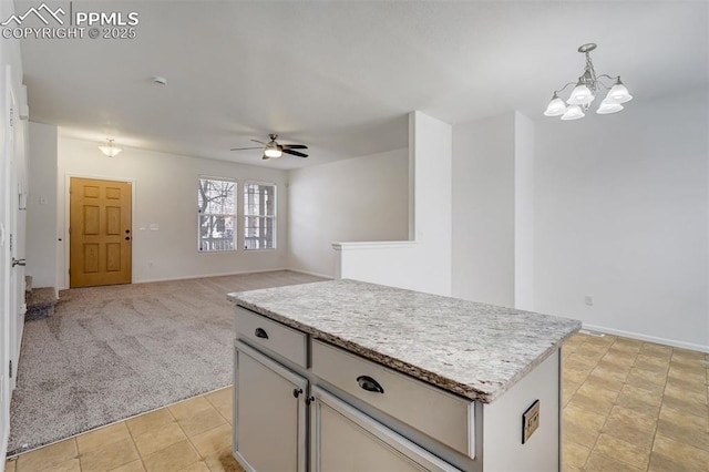 kitchen featuring a kitchen island, ceiling fan with notable chandelier, light carpet, and hanging light fixtures