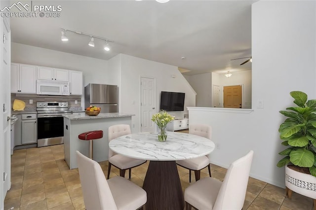 kitchen featuring stainless steel appliances, a center island, ceiling fan, white cabinets, and tasteful backsplash