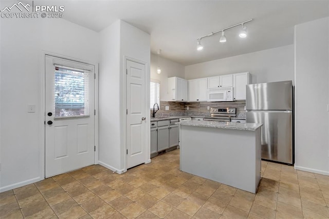 kitchen featuring white cabinetry, tasteful backsplash, light stone countertops, a kitchen island, and appliances with stainless steel finishes