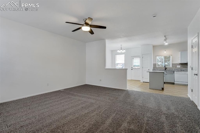 unfurnished living room featuring ceiling fan with notable chandelier, light carpet, and sink