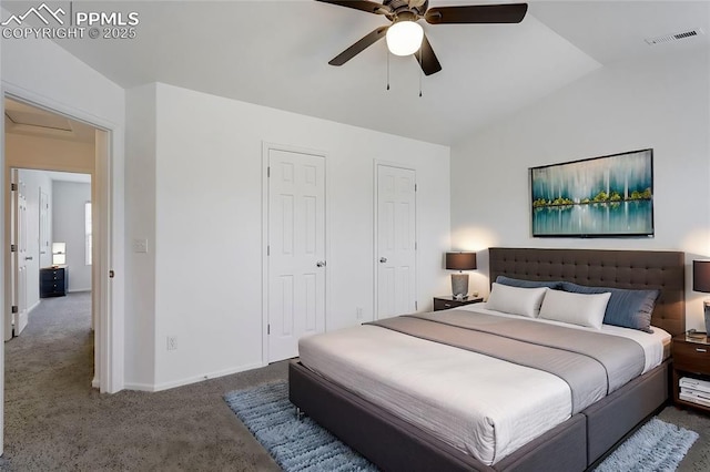 carpeted bedroom with ceiling fan, vaulted ceiling, and two closets