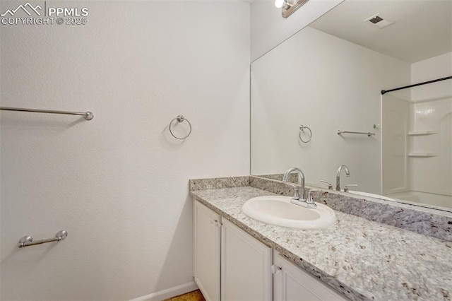 bathroom featuring walk in shower and vanity