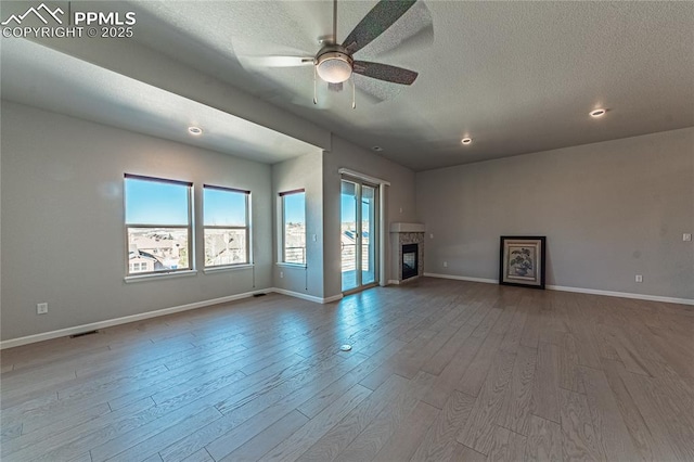 unfurnished living room with a textured ceiling, ceiling fan, and wood-type flooring