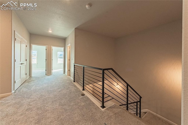 hallway featuring a textured ceiling and carpet flooring