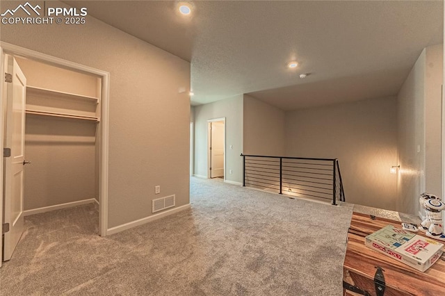 bedroom featuring a walk in closet, a closet, and carpet flooring