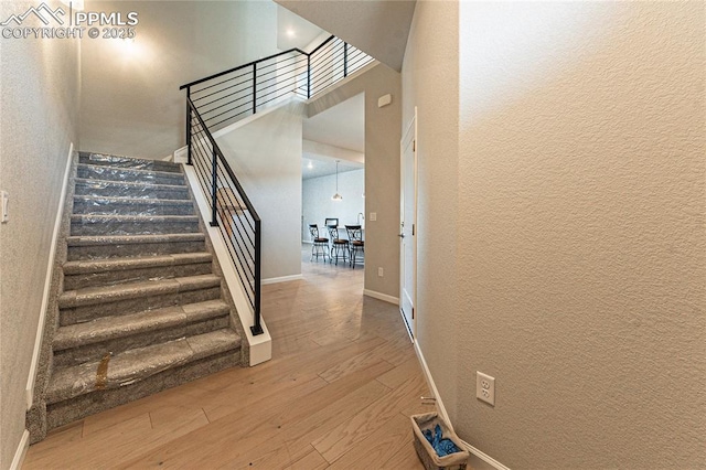 staircase with wood-type flooring and a high ceiling