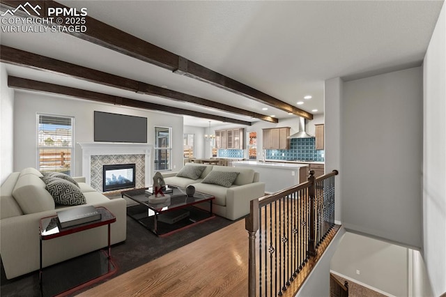 living room with a tiled fireplace, hardwood / wood-style flooring, and beam ceiling