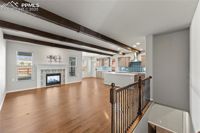 living room featuring beam ceiling, light hardwood / wood-style floors, and a tile fireplace