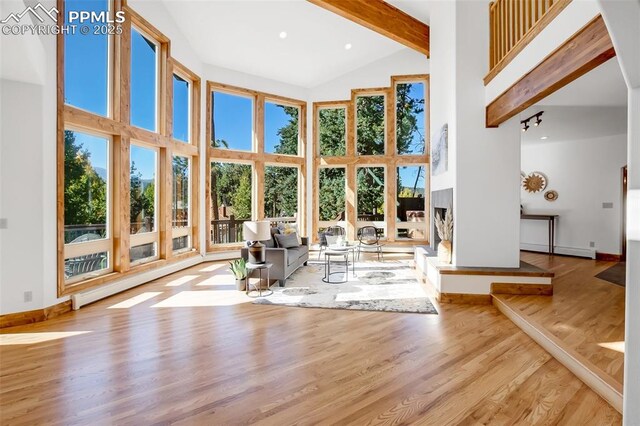 unfurnished living room featuring beam ceiling, a wealth of natural light, and high vaulted ceiling