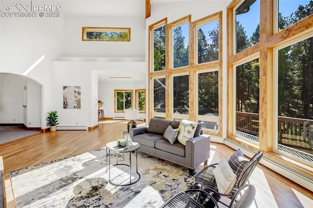 living room featuring a high ceiling, a baseboard radiator, and hardwood / wood-style floors