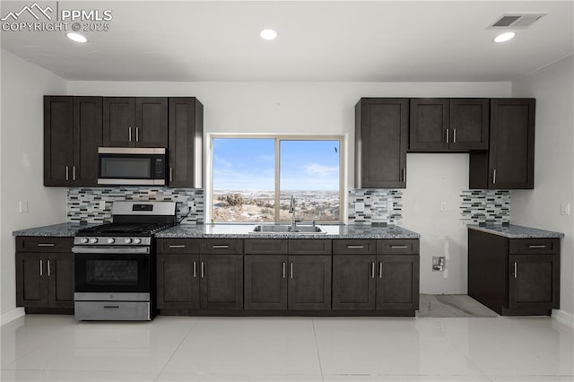 kitchen with appliances with stainless steel finishes, dark brown cabinets, backsplash, and sink