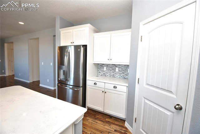 kitchen featuring dark hardwood / wood-style flooring, stainless steel fridge with ice dispenser, decorative backsplash, and white cabinetry