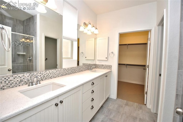 bathroom with a shower with shower door, tasteful backsplash, and vanity