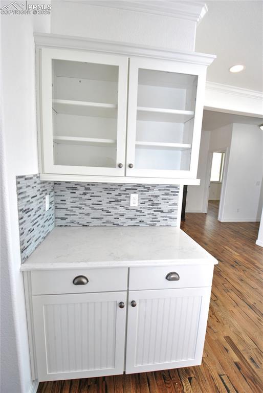 room details featuring hardwood / wood-style floors, crown molding, and decorative backsplash