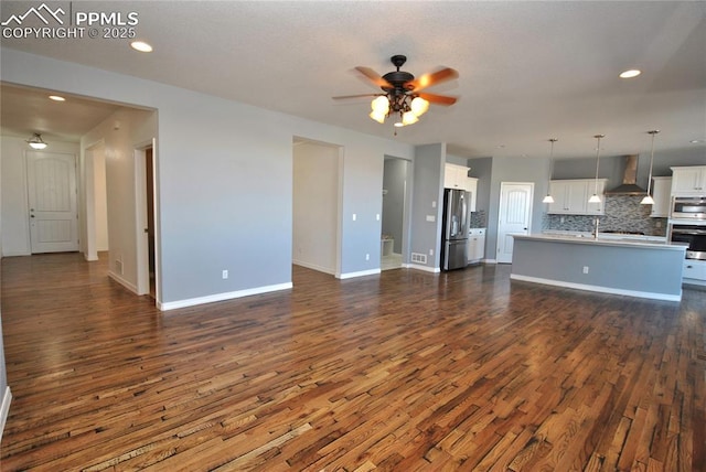 unfurnished living room with ceiling fan, dark wood-type flooring, and sink