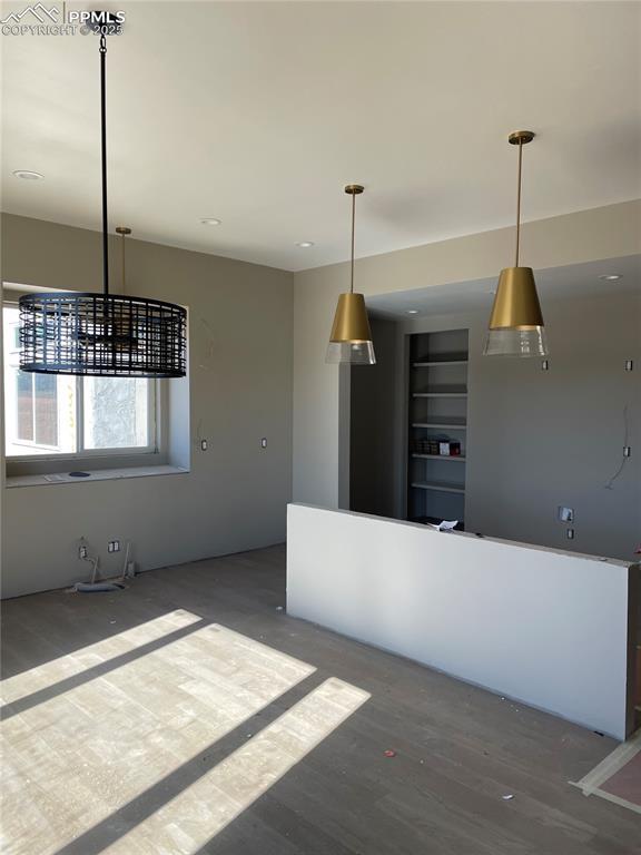 kitchen with built in shelves, hardwood / wood-style floors, and hanging light fixtures