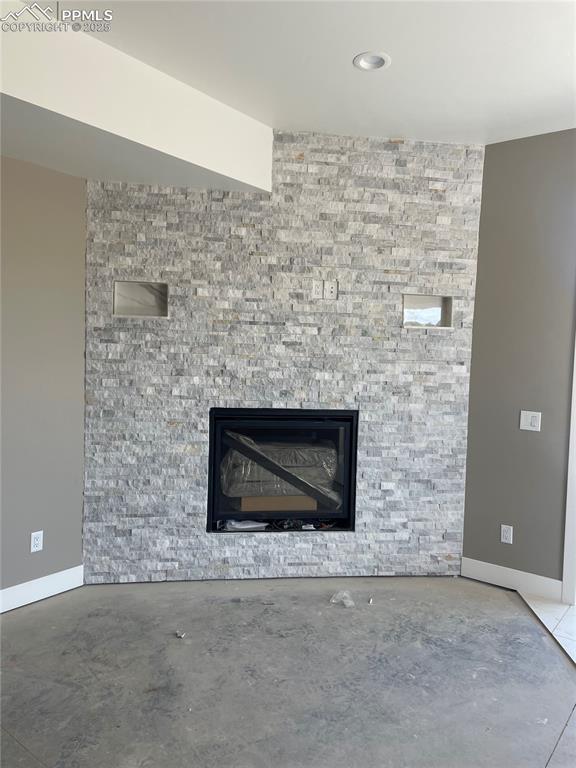 room details with a stone fireplace, baseboards, and concrete floors