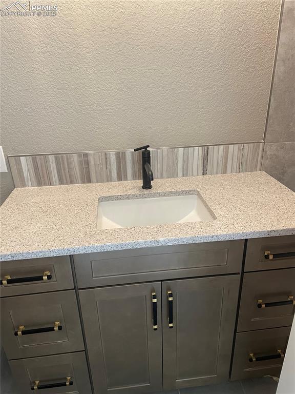 bathroom with a textured wall and vanity
