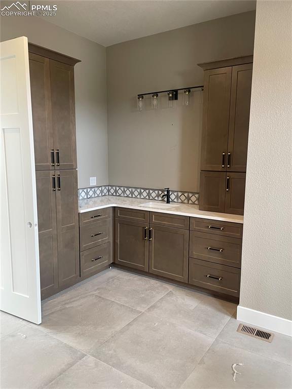 kitchen with visible vents, light countertops, a sink, and dark brown cabinets