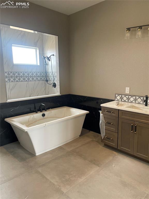 bathroom with vanity, a freestanding tub, and a tile shower