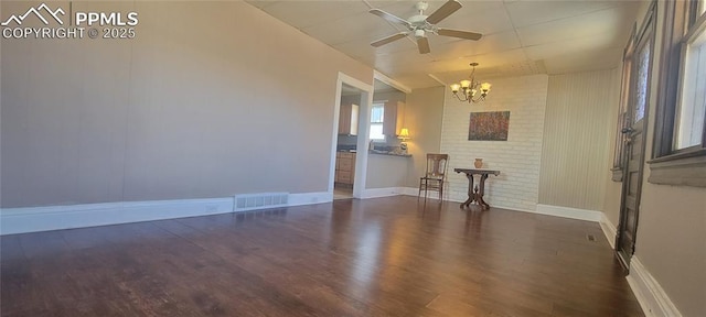 empty room with baseboards, visible vents, wood finished floors, and ceiling fan with notable chandelier