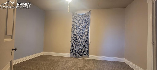 spare room with dark carpet and baseboards