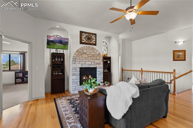 living room with ceiling fan, hardwood / wood-style flooring, and a stone fireplace