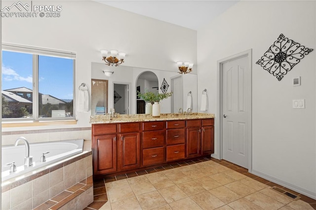 bathroom featuring tiled bath, vanity, and tile patterned flooring