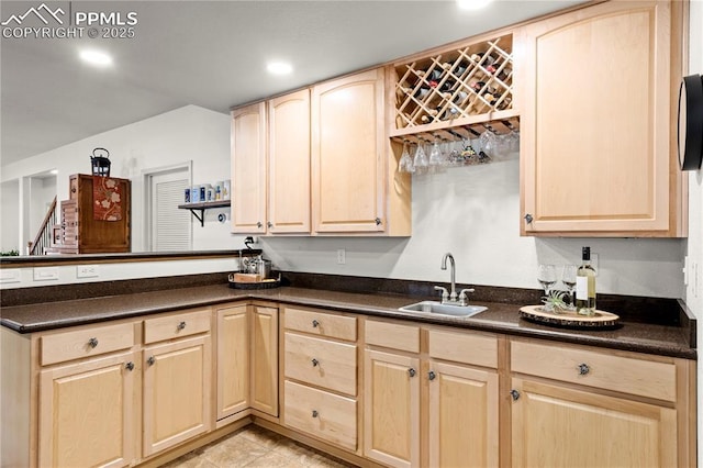 kitchen with light tile patterned floors, light brown cabinetry, kitchen peninsula, and sink